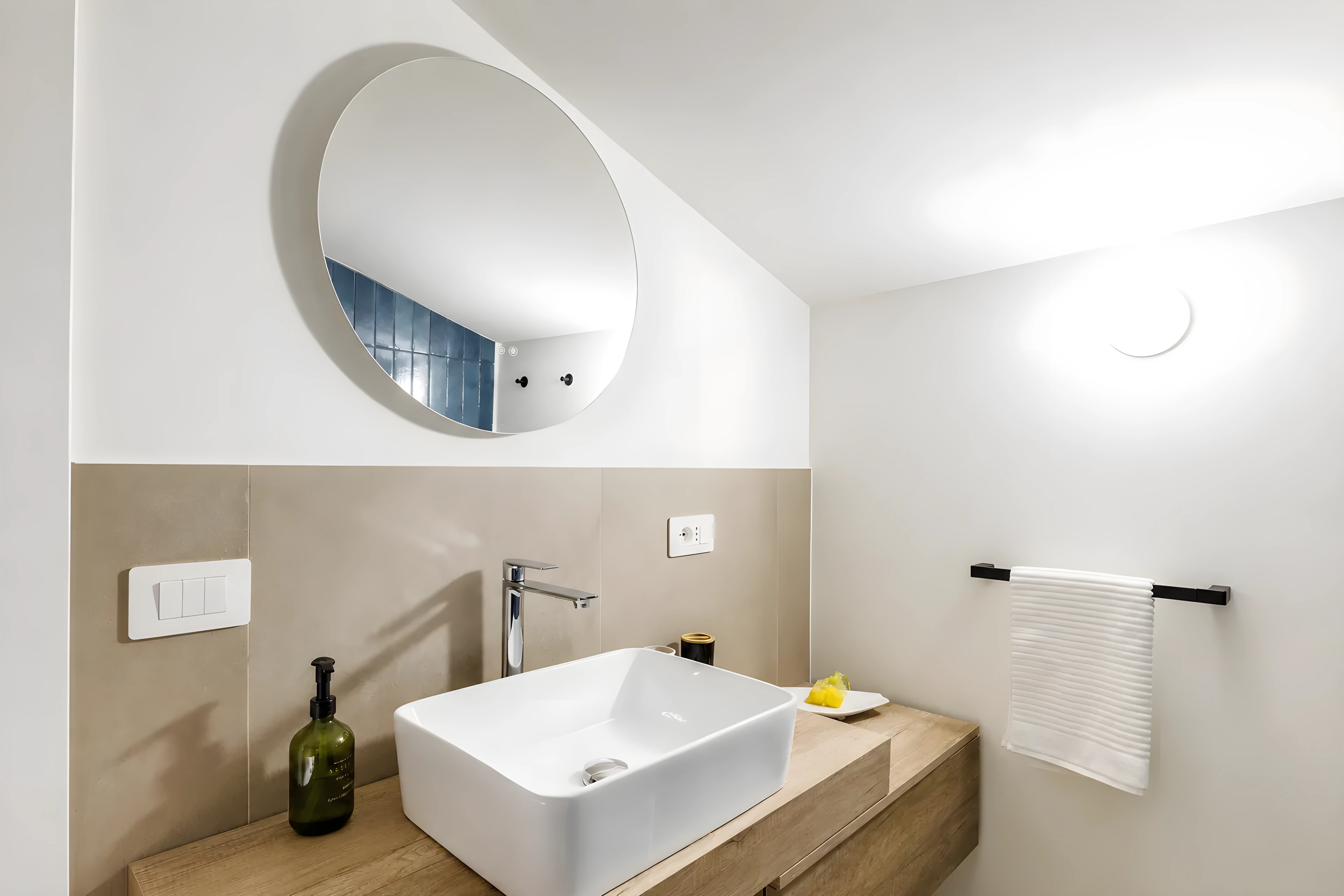Bagno con piano in legno, lavabo d’appoggio e specchio tondo