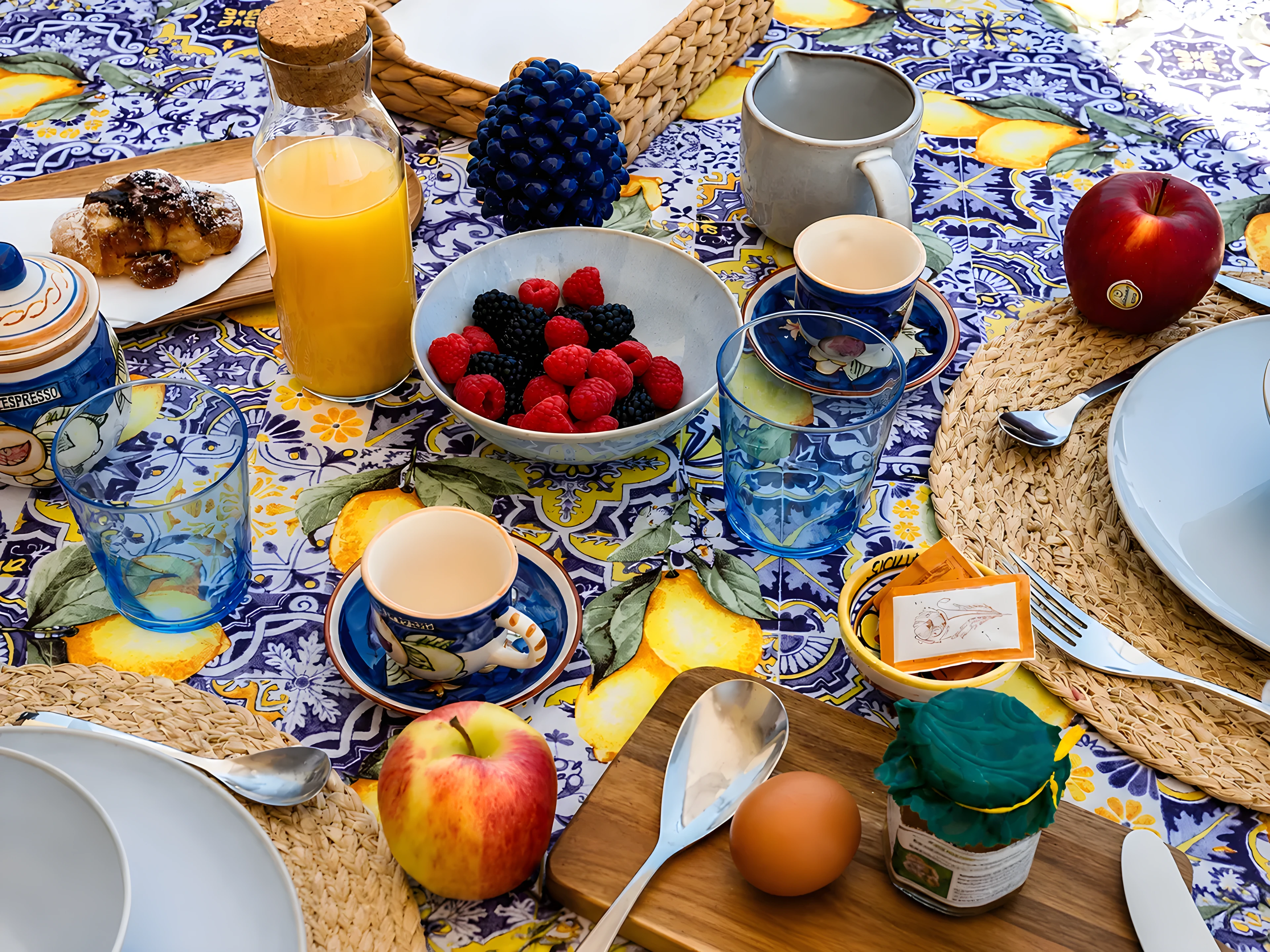 Tavola della colazione con ceramiche siciliane, frutta fresca e caffettiera