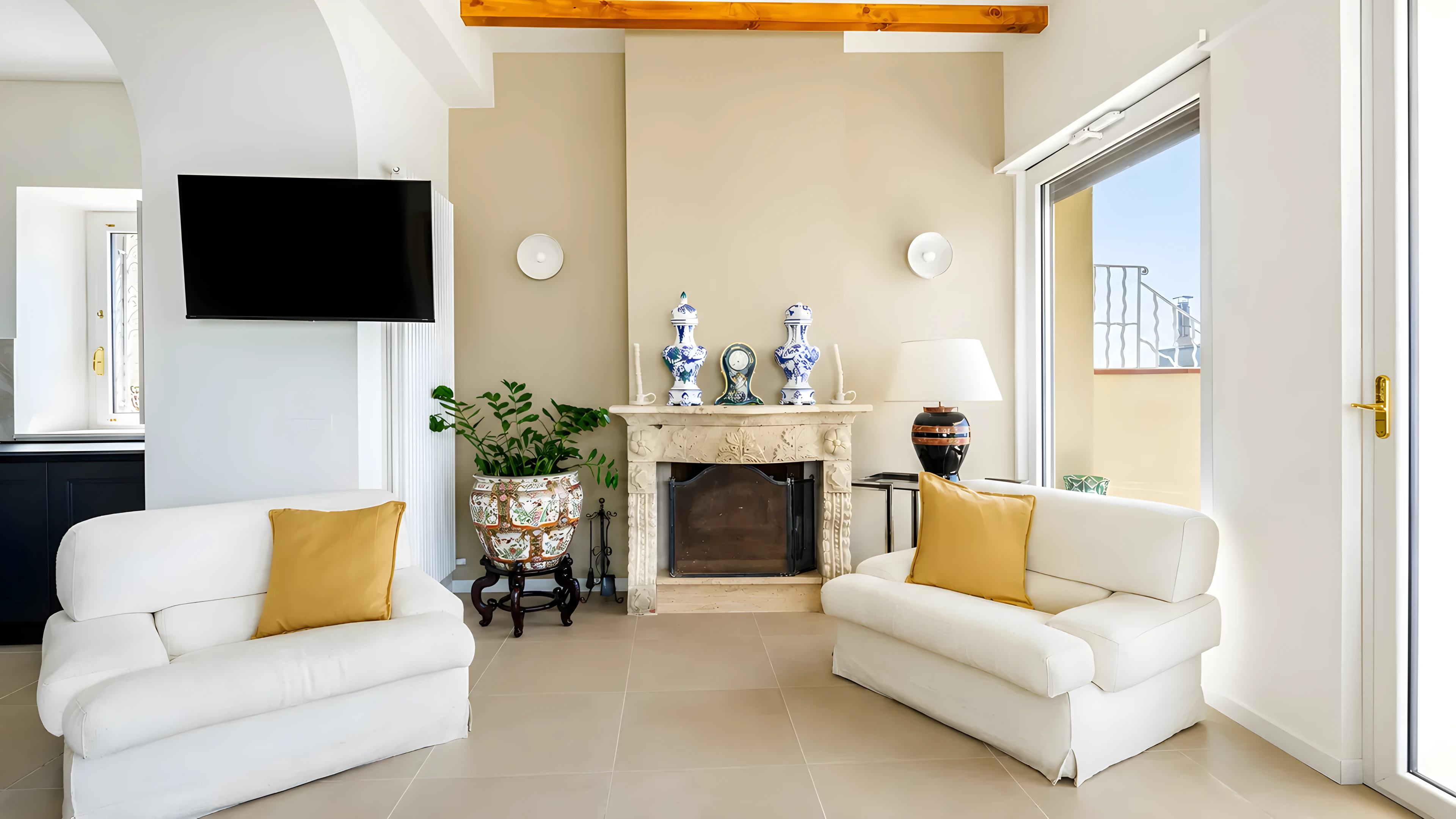 Il salone di Casa Awaya con camino in pietra, poltrone chiare e ceramiche di famiglia